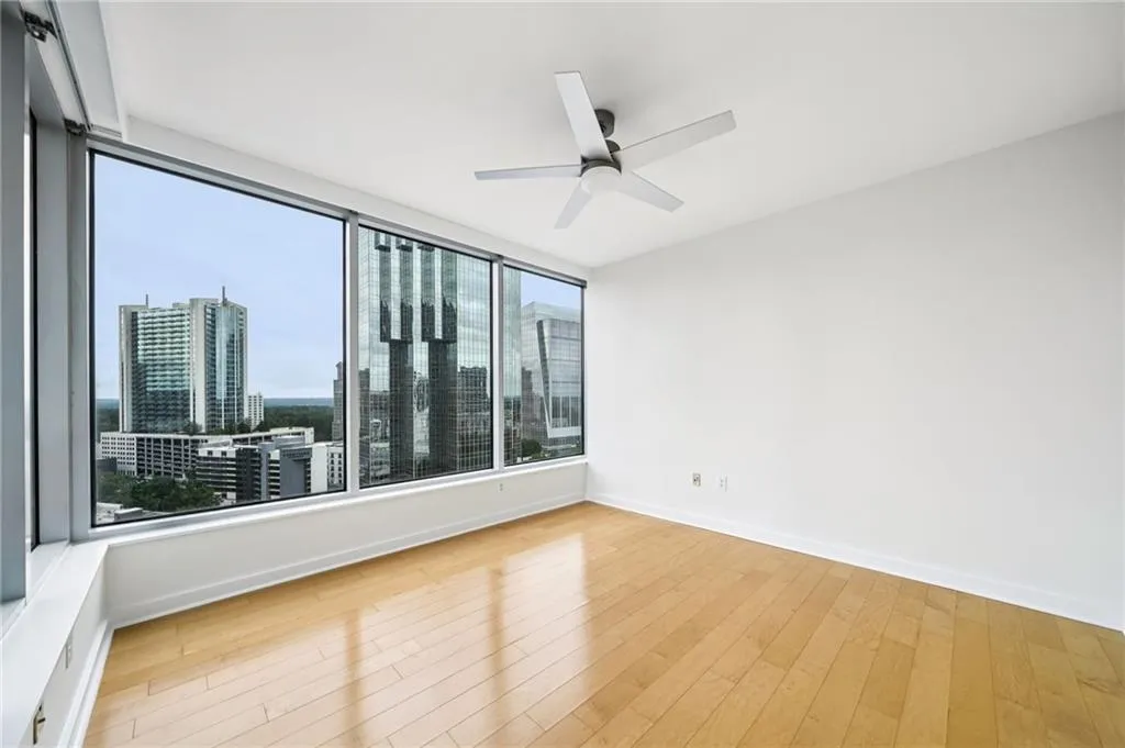 Empty room featuring a skyline view, hardwood / wood-style floors, and a ceiling fan