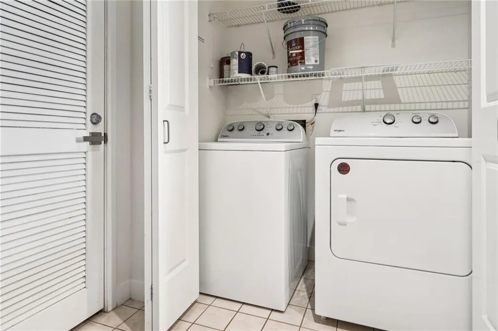 Laundry area with light tile patterned flooring and washer and clothes dryer