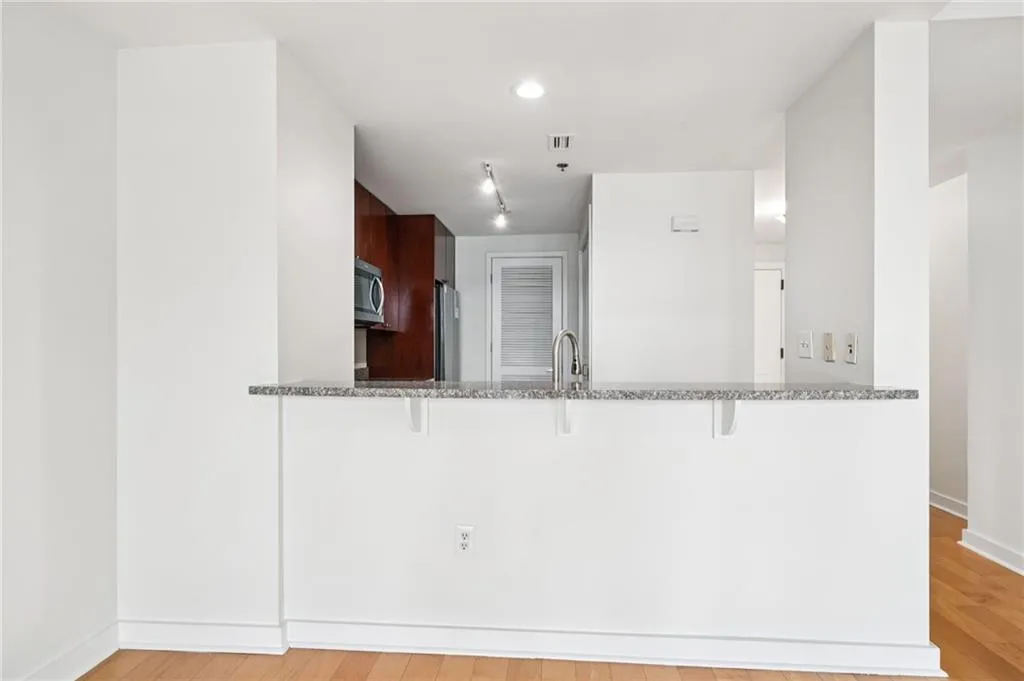 Kitchen with a breakfast bar area, light stone countertops, light wood-style floors, a peninsula, and recessed lighting