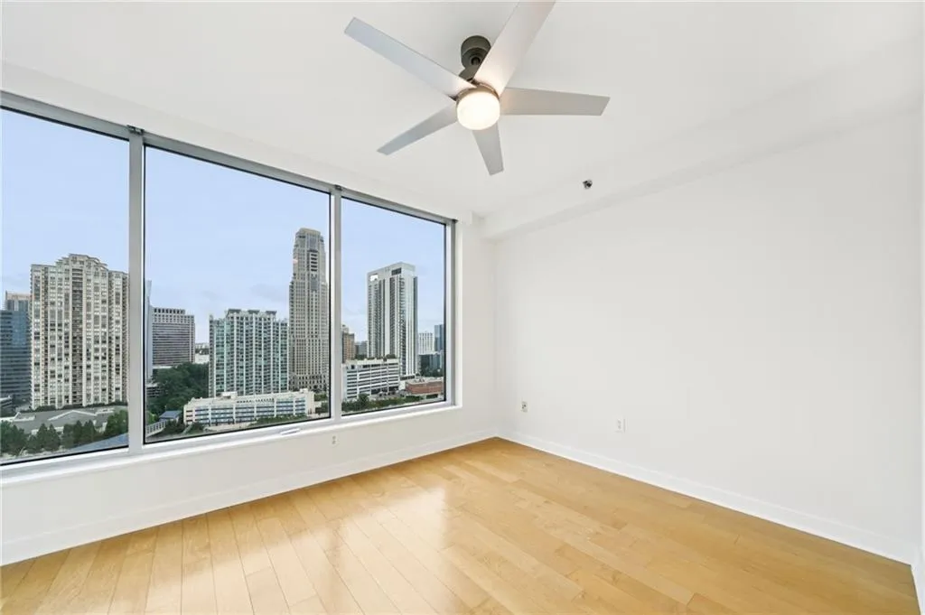 Unfurnished room with a skyline view, light wood-style floors, and ceiling fan