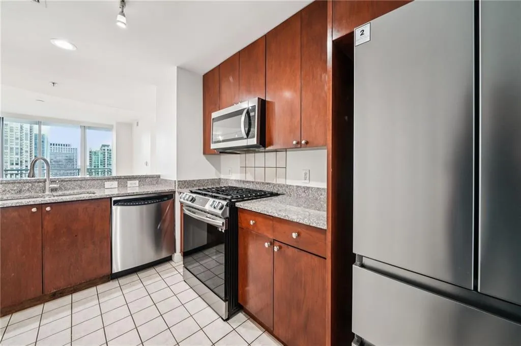 Kitchen featuring stainless steel appliances, light stone countertops, light tile patterned floors, recessed lighting, and a city view