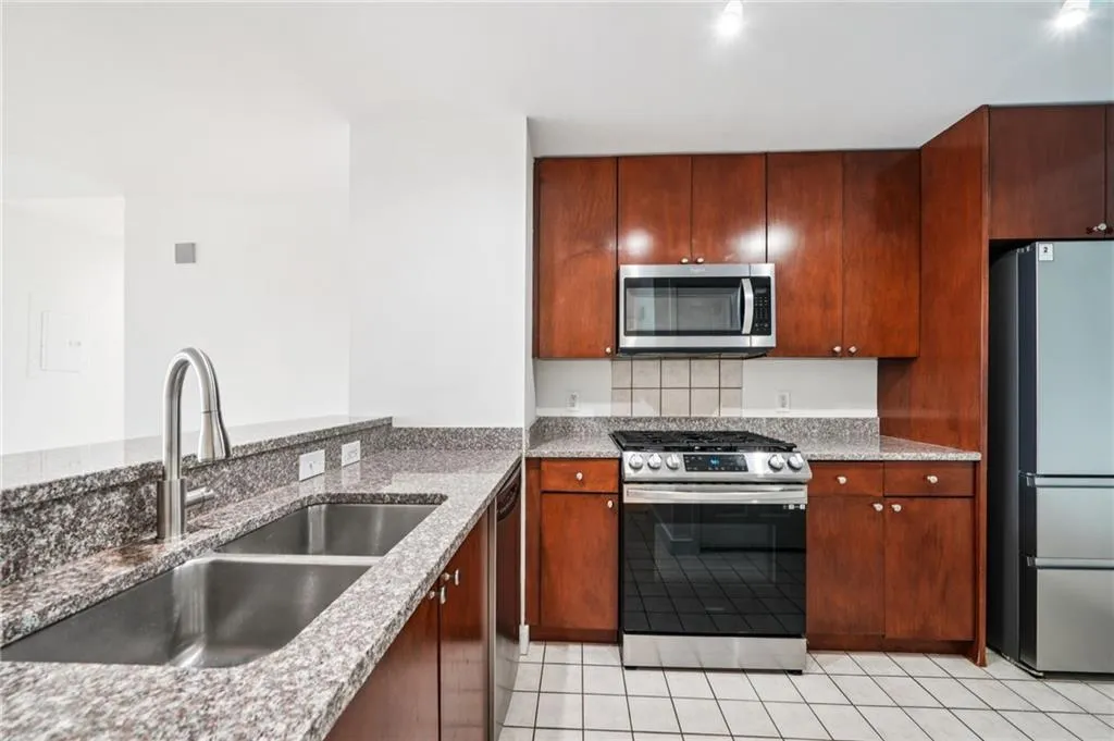 Kitchen with stainless steel appliances, light tile patterned floors, and dark stone countertops