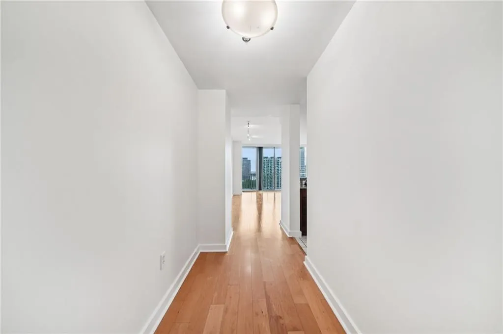 Corridor with light wood-type flooring and baseboards