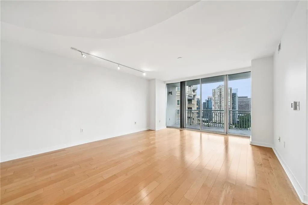 Unfurnished room with a skyline view, expansive windows, light wood-style flooring, and track lighting
