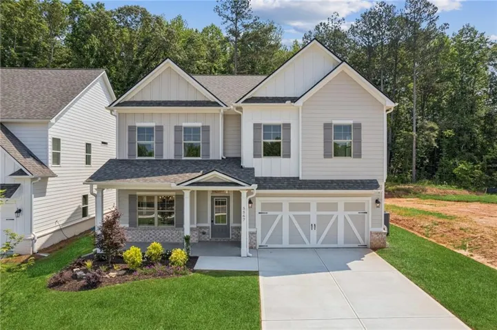 Contemporary two-story residence featuring a covered front porch, a two-car garage with decorative doors, and a combination of horizontal siding and board-and-batten accents