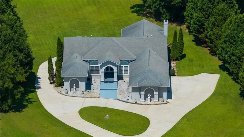 Exterior showcasing a light blue stucco finish with stone accents and a multi-level gray shingle roof
