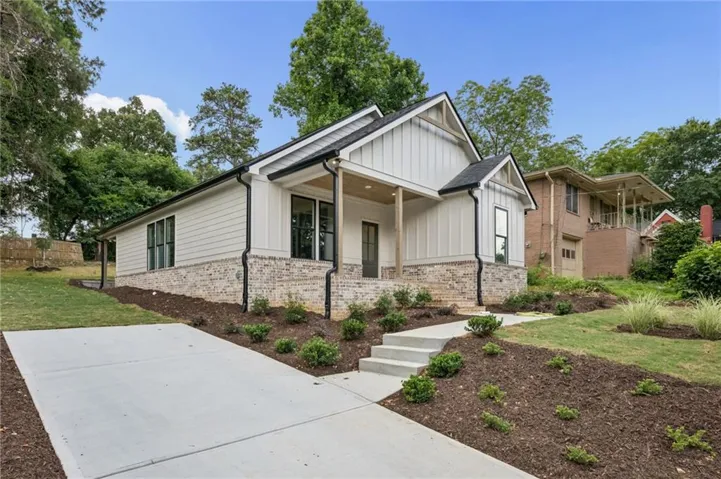 Contemporary facade with board and batten siding, brick skirting, and black-framed windows