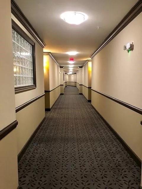 Hallway with dark carpet and ornamental molding