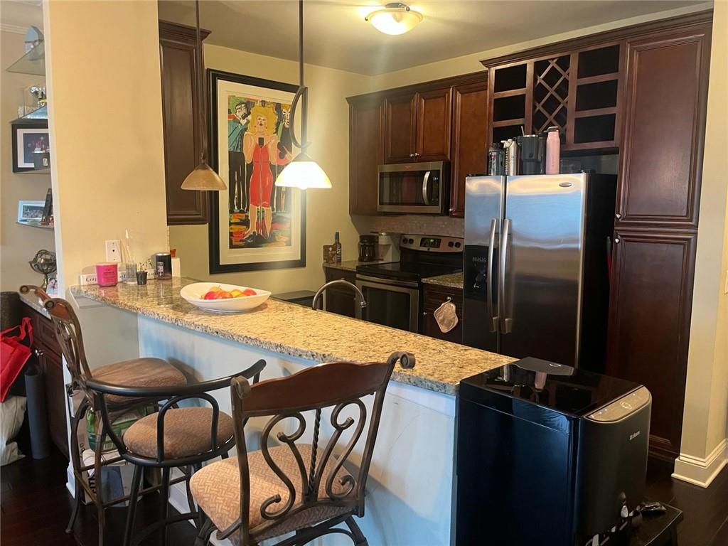 Kitchen with pendant lighting, appliances with stainless steel finishes, and a breakfast bar