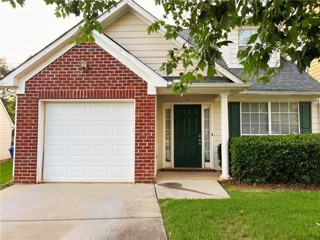Brick and siding exterior with a dark green entry door