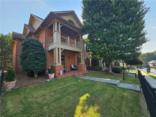Brick exterior with a prominent two-story front porch, featuring a second-story balcony with railings