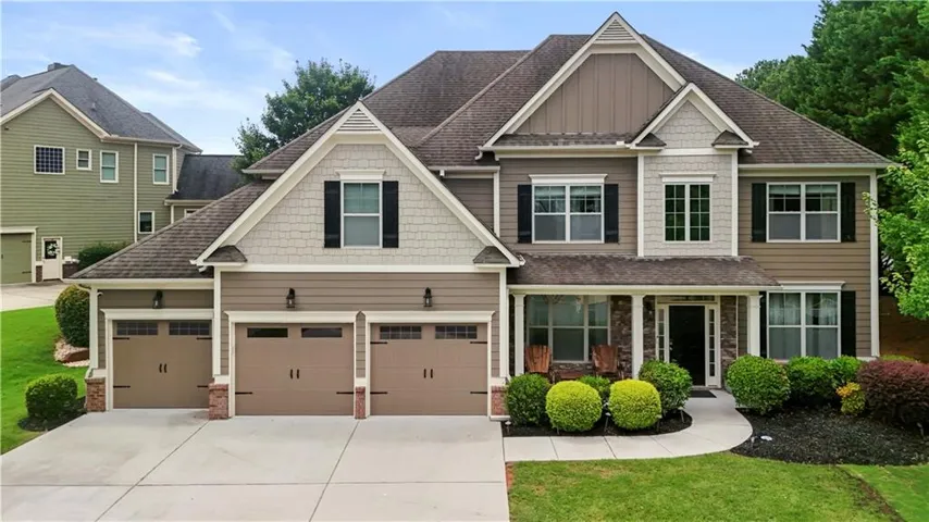 Two-story home with a multi-gabled roofline, stone facade accents, and a three-car garage