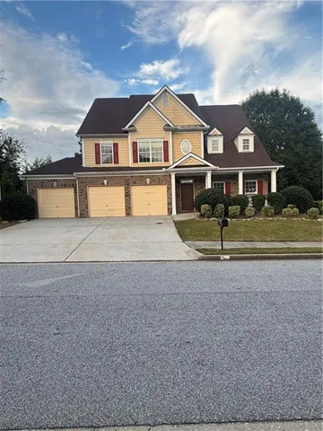 Two-story residence featuring a brick and siding exterior, a three-car garage, and a covered front entry