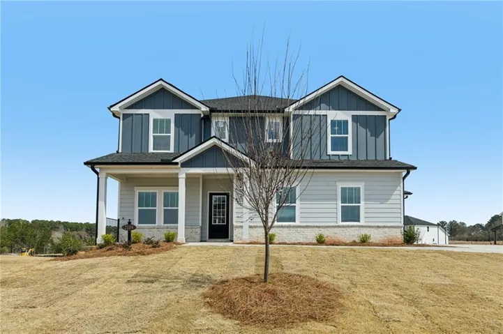 Craftsman-style house featuring board and batten siding, covered porch, brick siding, and a front yard