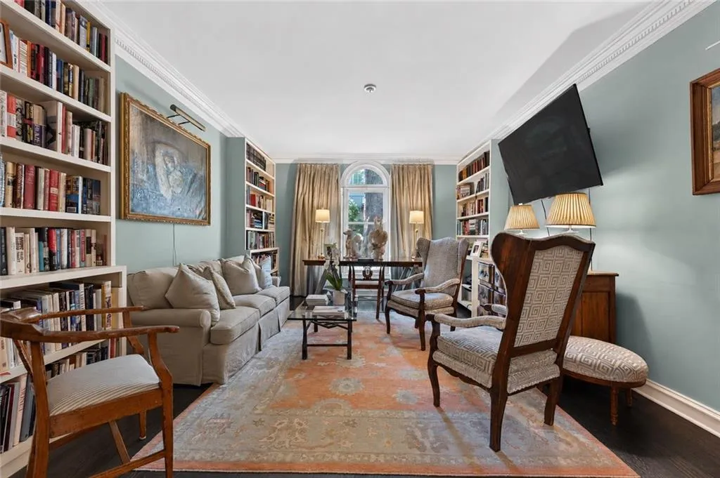 Built-in shelving, crown molding, arched window, dark wood-finish flooring, and recessed lighting