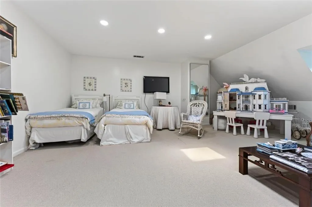 Recessed lighting illuminates the carpeted flooring and white painted walls