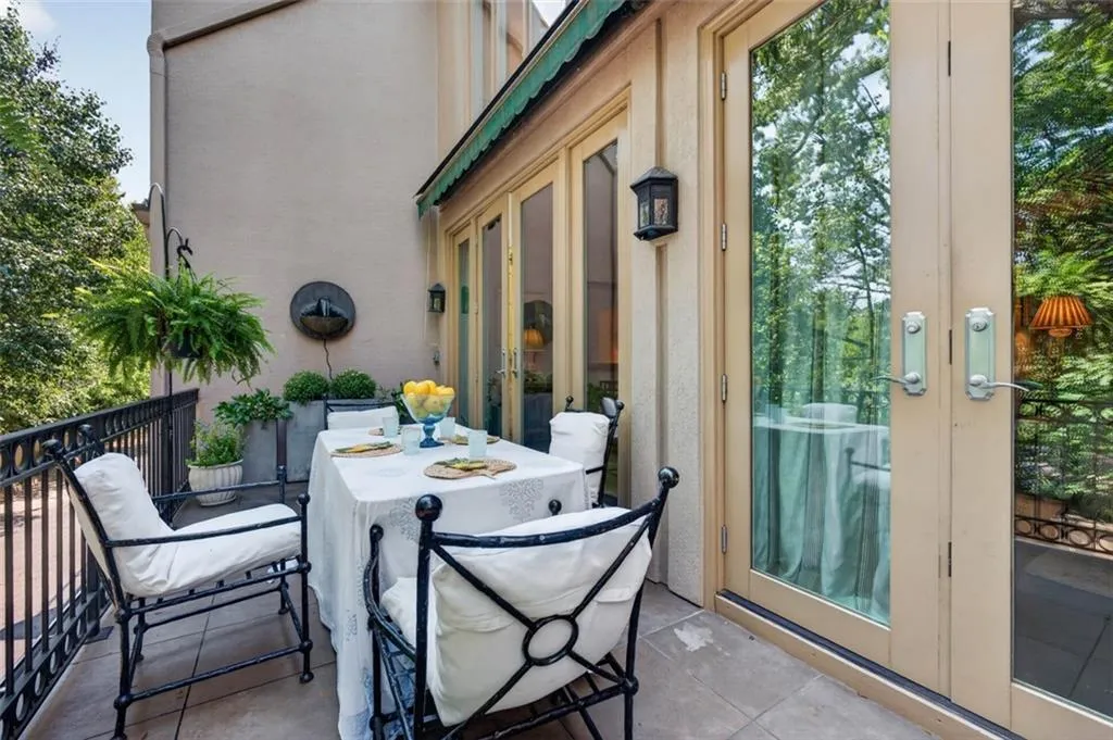 Exterior balcony featuring a wall-mounted water feature, black wrought iron railing, and a green retractable awning