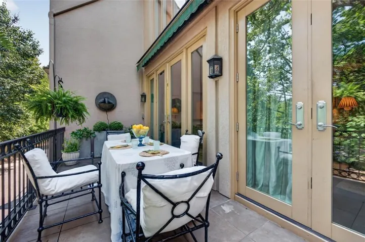 Exterior balcony featuring a wall-mounted water feature, black wrought iron railing, and a green retractable awning