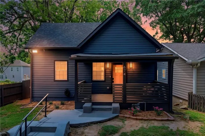 Contemporary exterior featuring blue siding, a covered front porch with dark horizontal slat railing, and a gabled roof