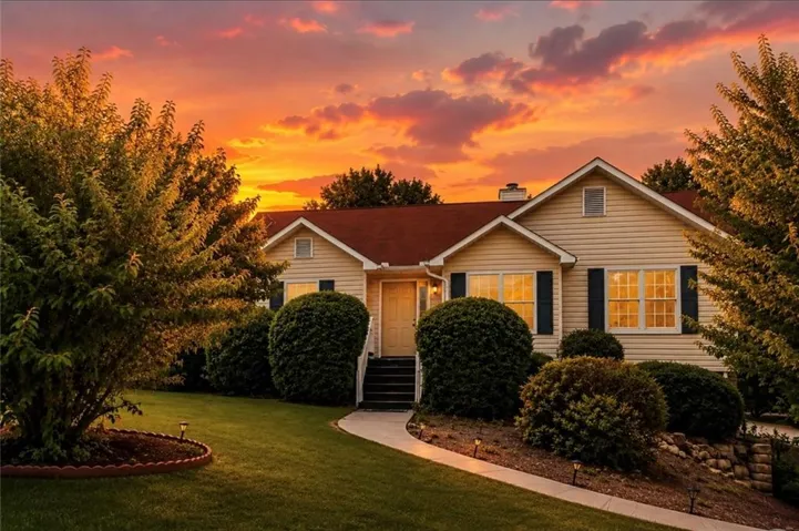 Siding exterior with dark shutters, gabled rooflines, a concrete walkway, and landscaped shrubbery