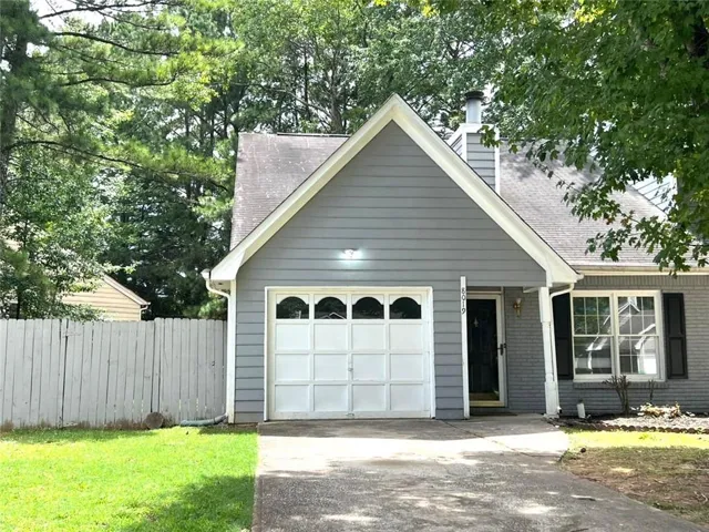 View of front facade with a garage, driveway, a shingled roof, and brick siding