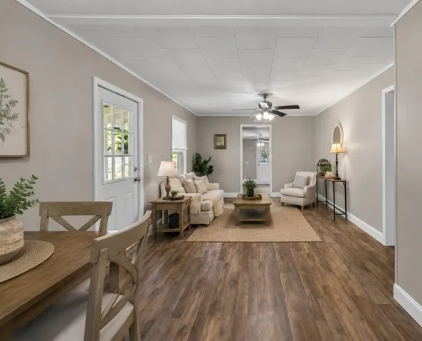 Virtual Staging pic shows Open-concept living area featuring wood-finish flooring, neutral wall tones, white trim, and a ceiling fan