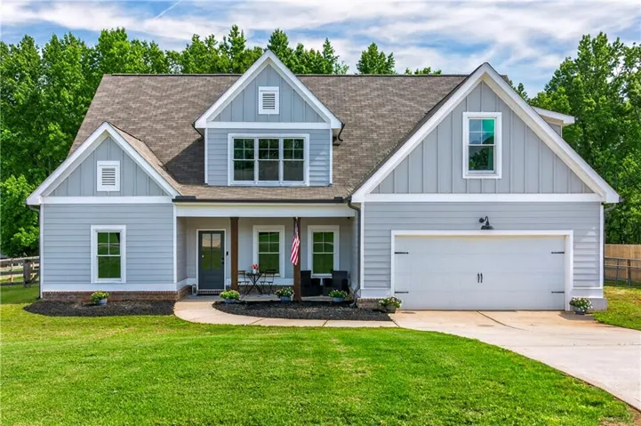 Craftsman-style exterior with light blue siding, a covered front porch with wood columns, an attached two-car garage, and a concrete driveway