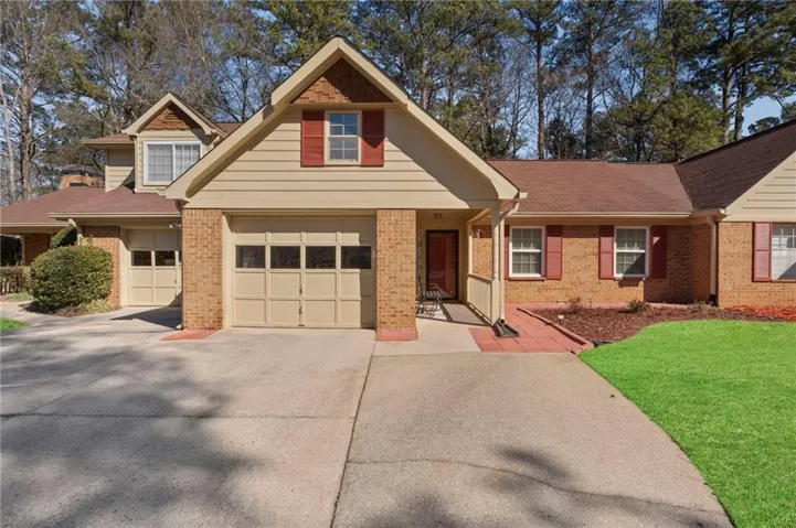 View of front of house with concrete driveway, a front yard, roof with shingles, and an attached garage