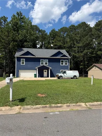 Two-story residence featuring blue siding, a two-car garage, and a white front door