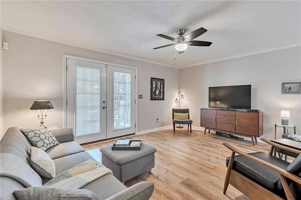 Enter into your Relaxing Main Living Area featuring french doors, light wood flooring, a ceiling fan, and ornamental molding.