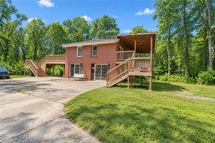Brick-clad exterior with multiple sliding glass doors and an expansive concrete parking area