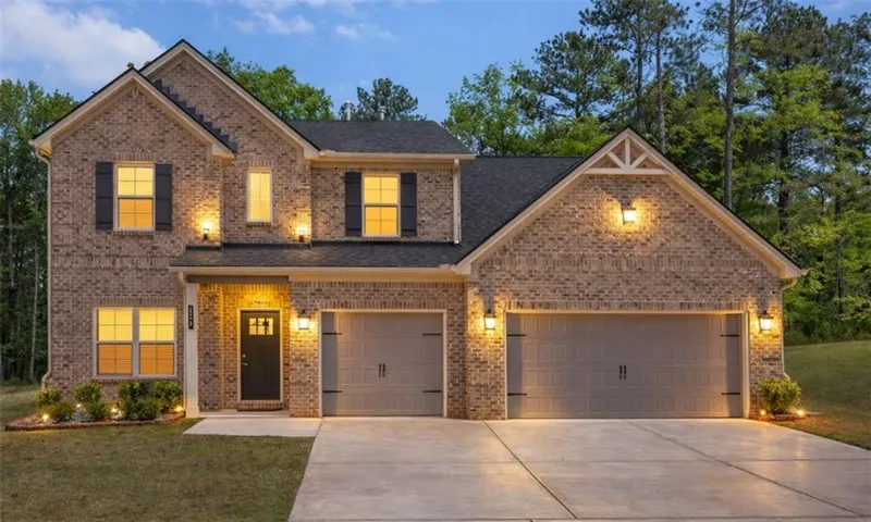 Brick Colonial-style home featuring a two-car garage with paneled doors, welcoming front entrance with sidelights, and multiple gabled rooflines