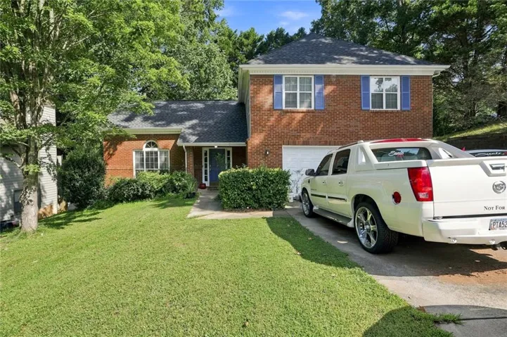 Brick facade, attached garage, blue front door, arched window, and established landscaping