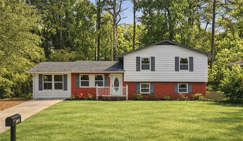 Split-level residence featuring a red brick lower level and white siding upper level