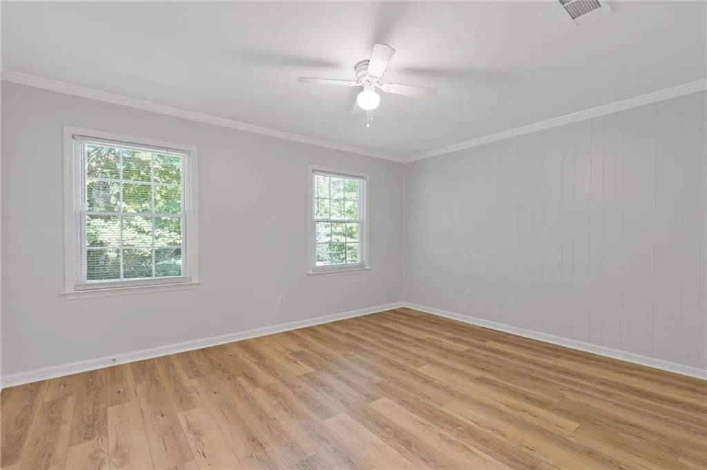 Unfurnished room with crown molding, ceiling fan, and light wood-style flooring