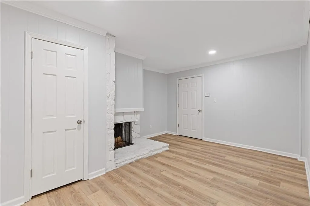 Unfurnished living room with ornamental molding, light wood-style flooring, a fireplace, and recessed lighting
