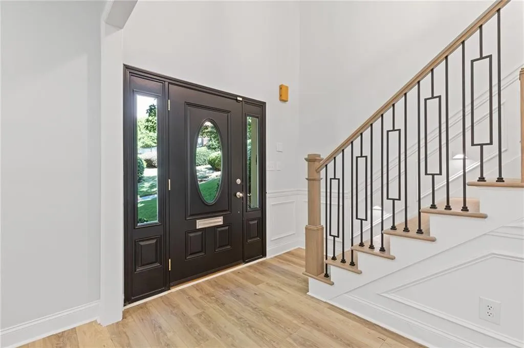 Expansive 2 story entryway with a decorative wall, wood finished floors, stairway, a wainscoted wall, and a towering ceiling