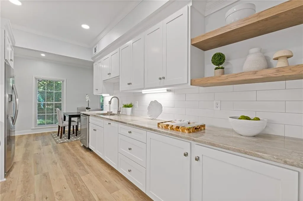 Kitchen with open shelves, crown molding, light wood-style flooring, white cabinetry, and decorative backsplash
