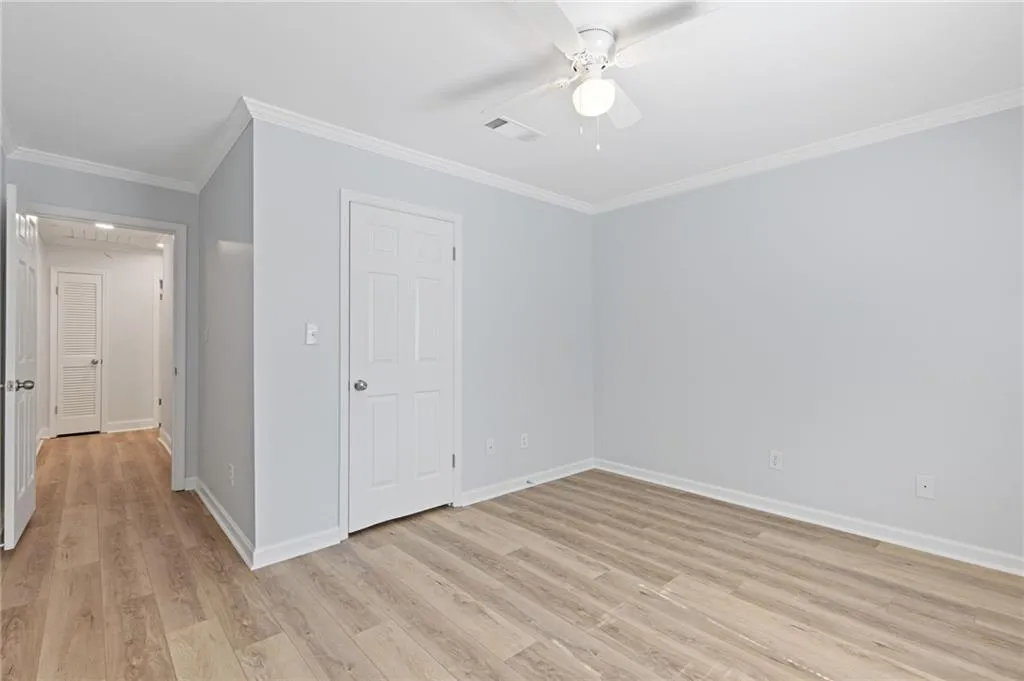 Unfurnished bedroom featuring ornamental molding, light wood finished floors, and ceiling fan