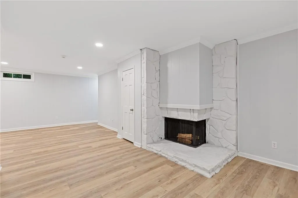 Unfurnished living room with wood finished floors, a fireplace, crown molding, wooden walls, and recessed lighting