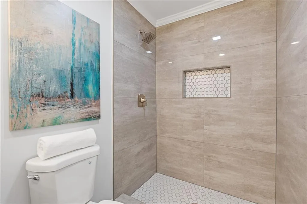Bathroom featuring tiled shower and ornamental molding