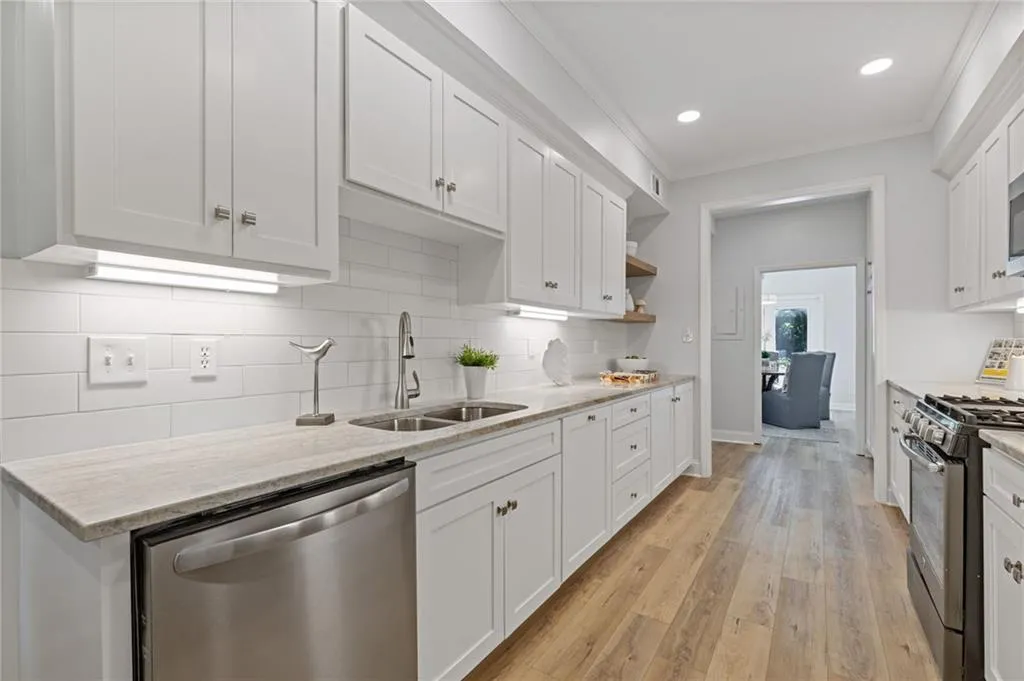 Kitchen featuring crown molding, stainless steel dishwasher, gas range oven, white cabinets, and light wood-style floors