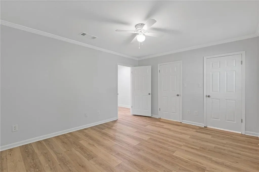 Unfurnished bedroom featuring crown molding, light wood-style flooring, and ceiling fan