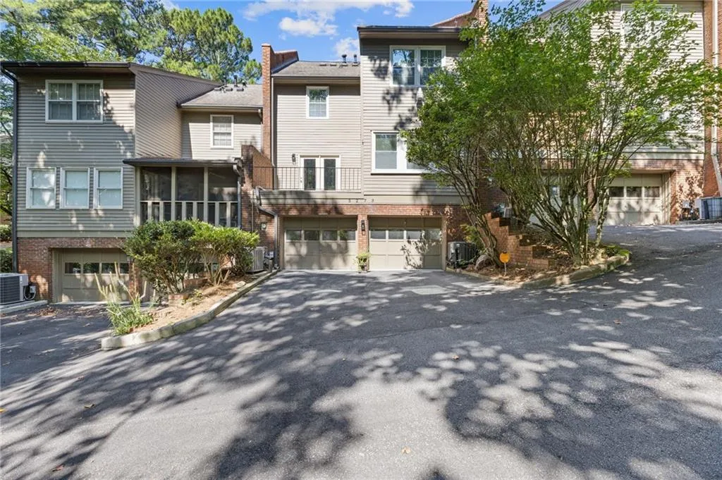 Back of property with brick siding, a garage, asphalt driveway, and a sunroom