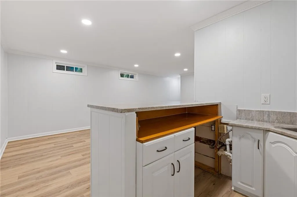 Wet Bar area with light wood-style floors, crown molding, recessed lighting, white cabinetry, and light countertops