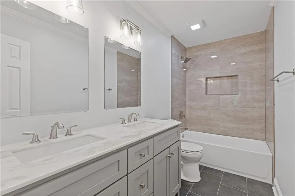 Bathroom featuring double vanity, ornamental molding, tile patterned floors, and shower / tub combination