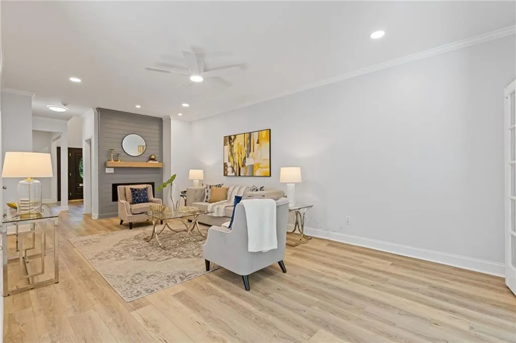 Living room featuring ceiling fan, ornamental molding, recessed lighting, light wood-style flooring, and a fireplace