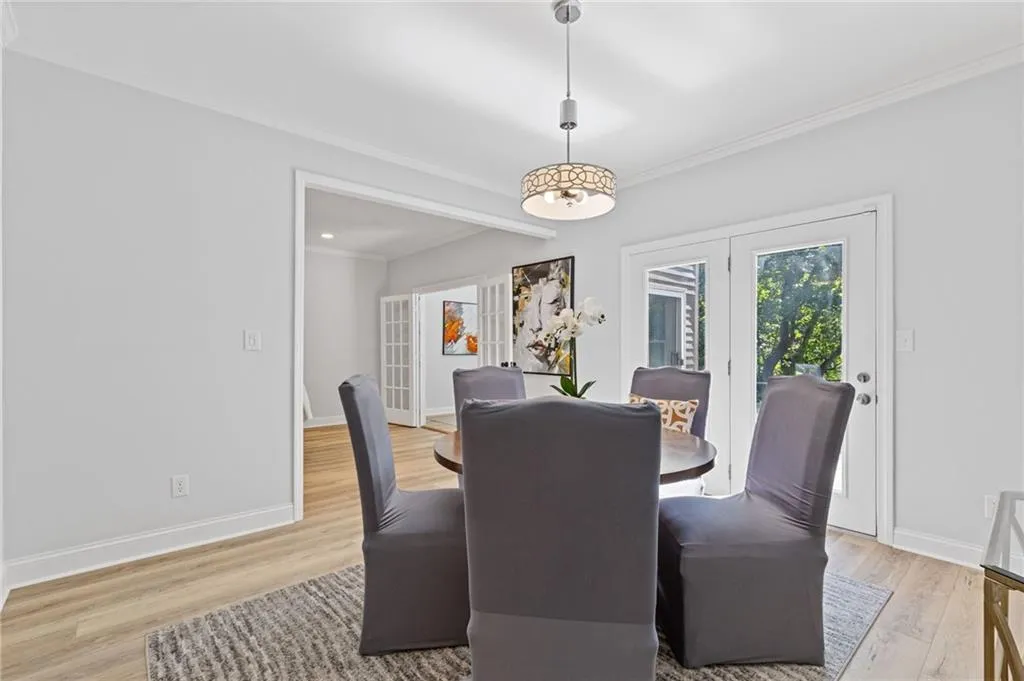 Dining space featuring french doors, ornamental molding, and light wood-style floors