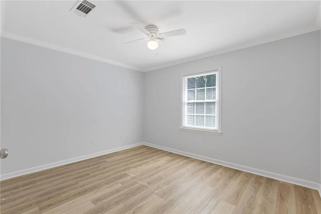 Spare room with crown molding, a ceiling fan, and light wood-style flooring
