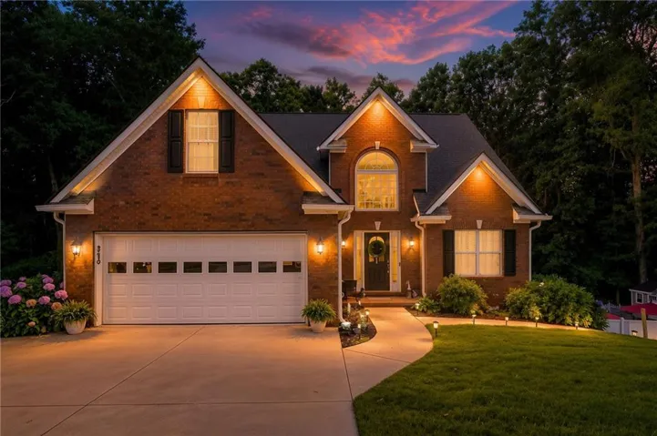 Brick exterior, arched window, two-car garage, concrete driveway, and a paved walkway
